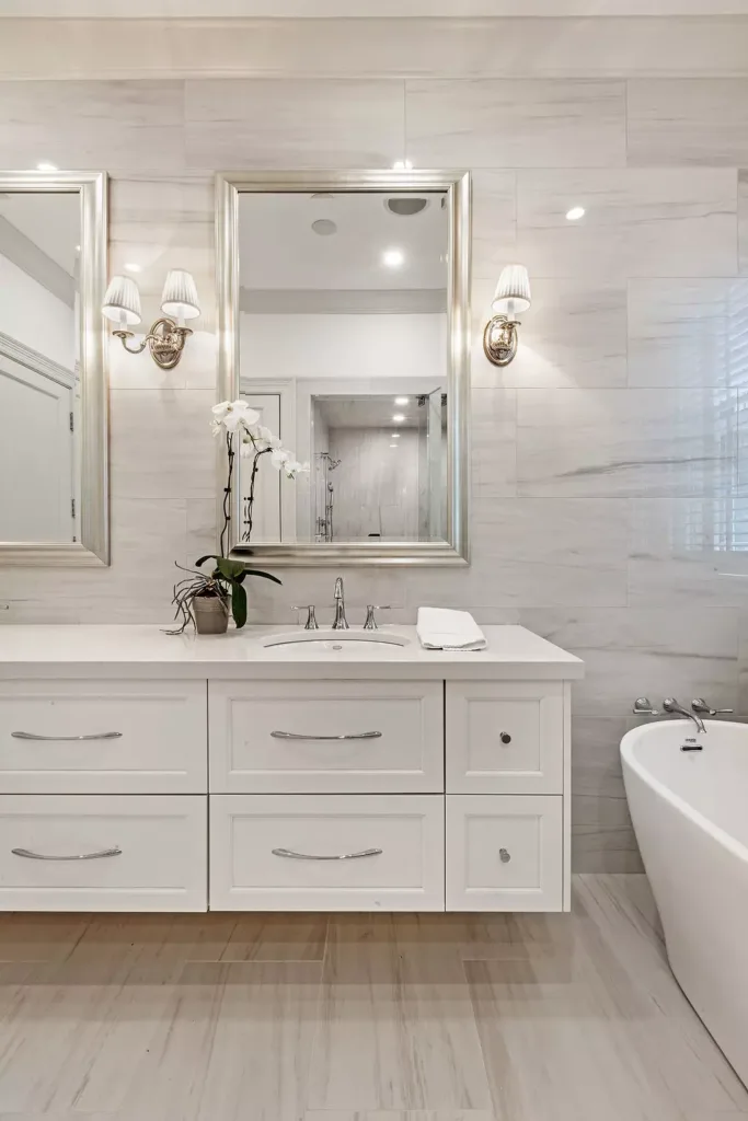 floating vanity (white) with a silver bathroom mirror above in this master bathroom remodel