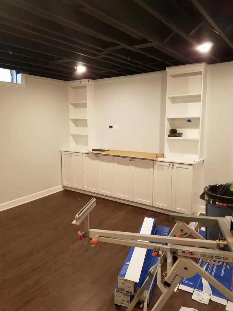 A room with white cabinets and wood floors undergoing kitchen renovation.