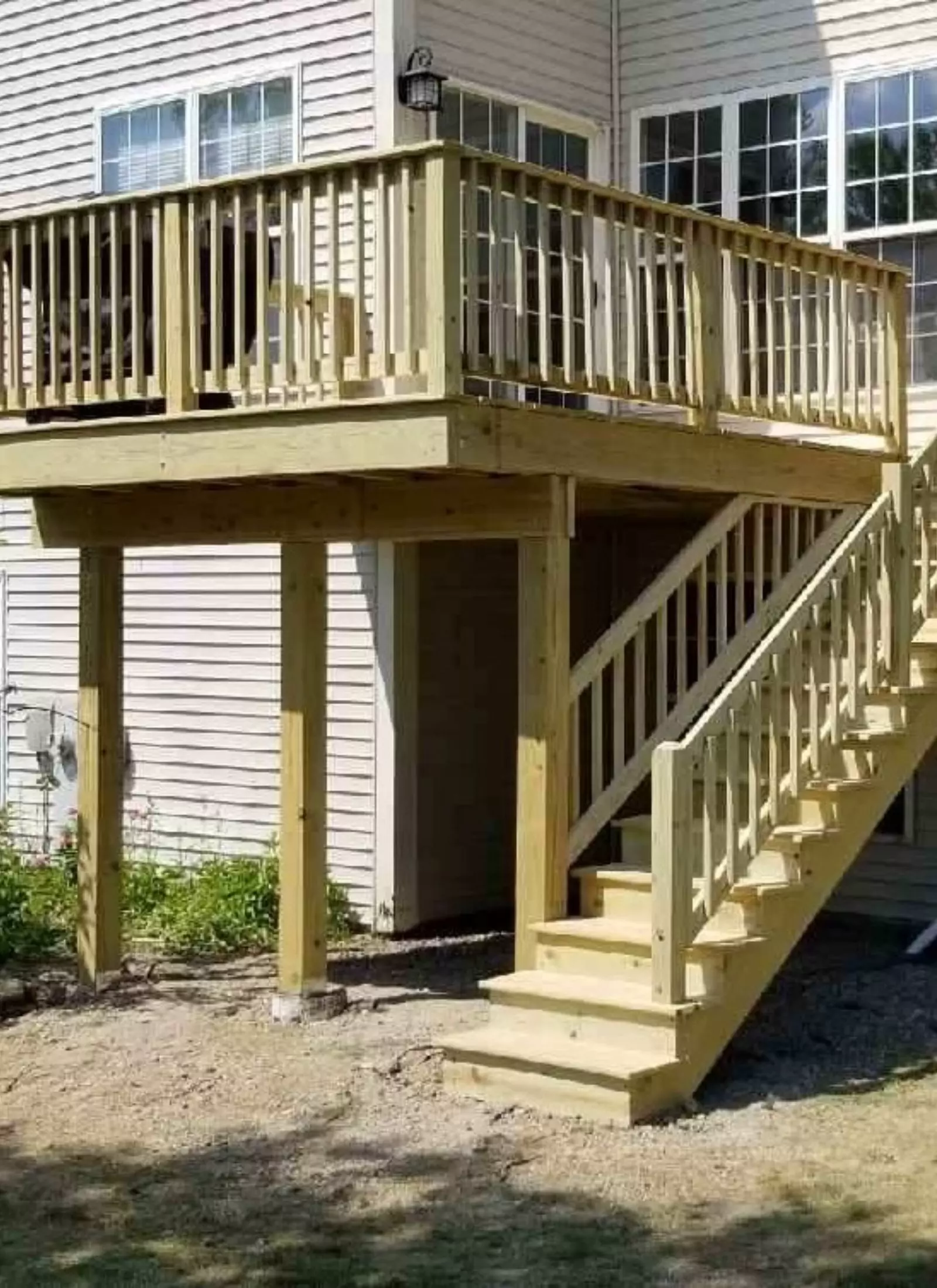 A wooden deck with stairs and railings in front of a house.