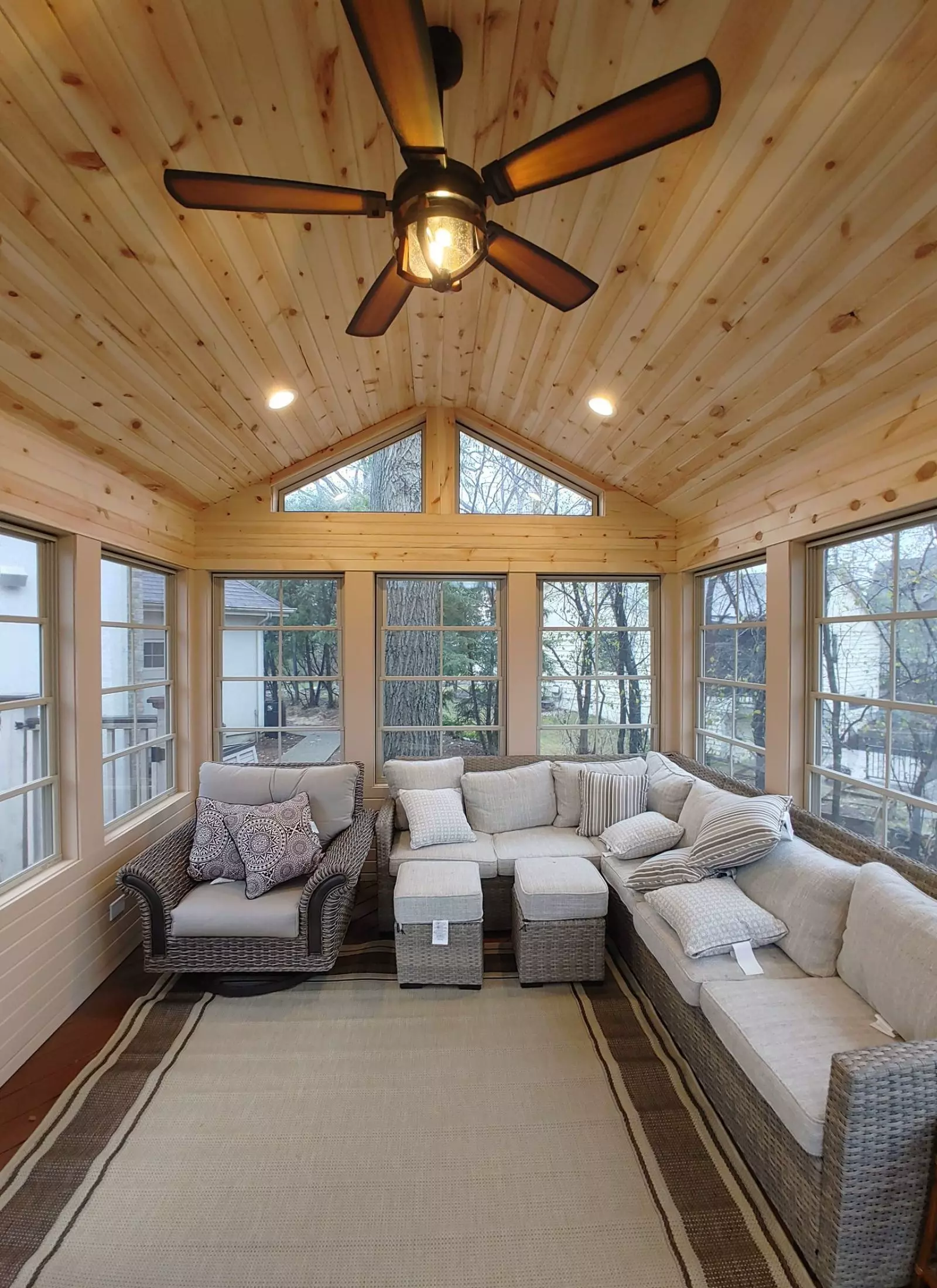 A sunroom with wicker furniture and a ceiling fan.