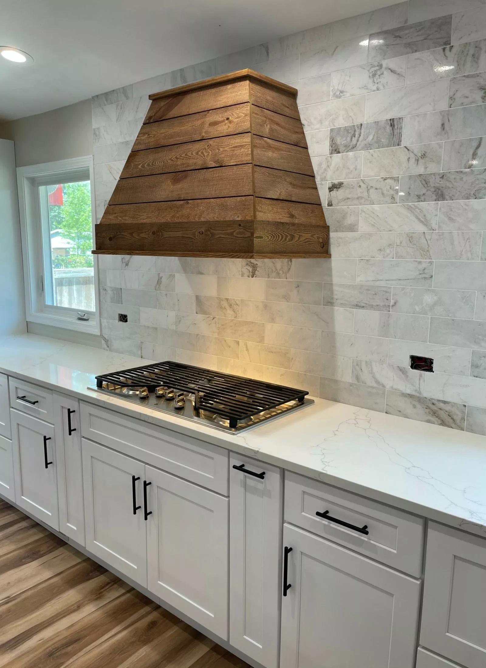 A white kitchen with a wood hood hood.