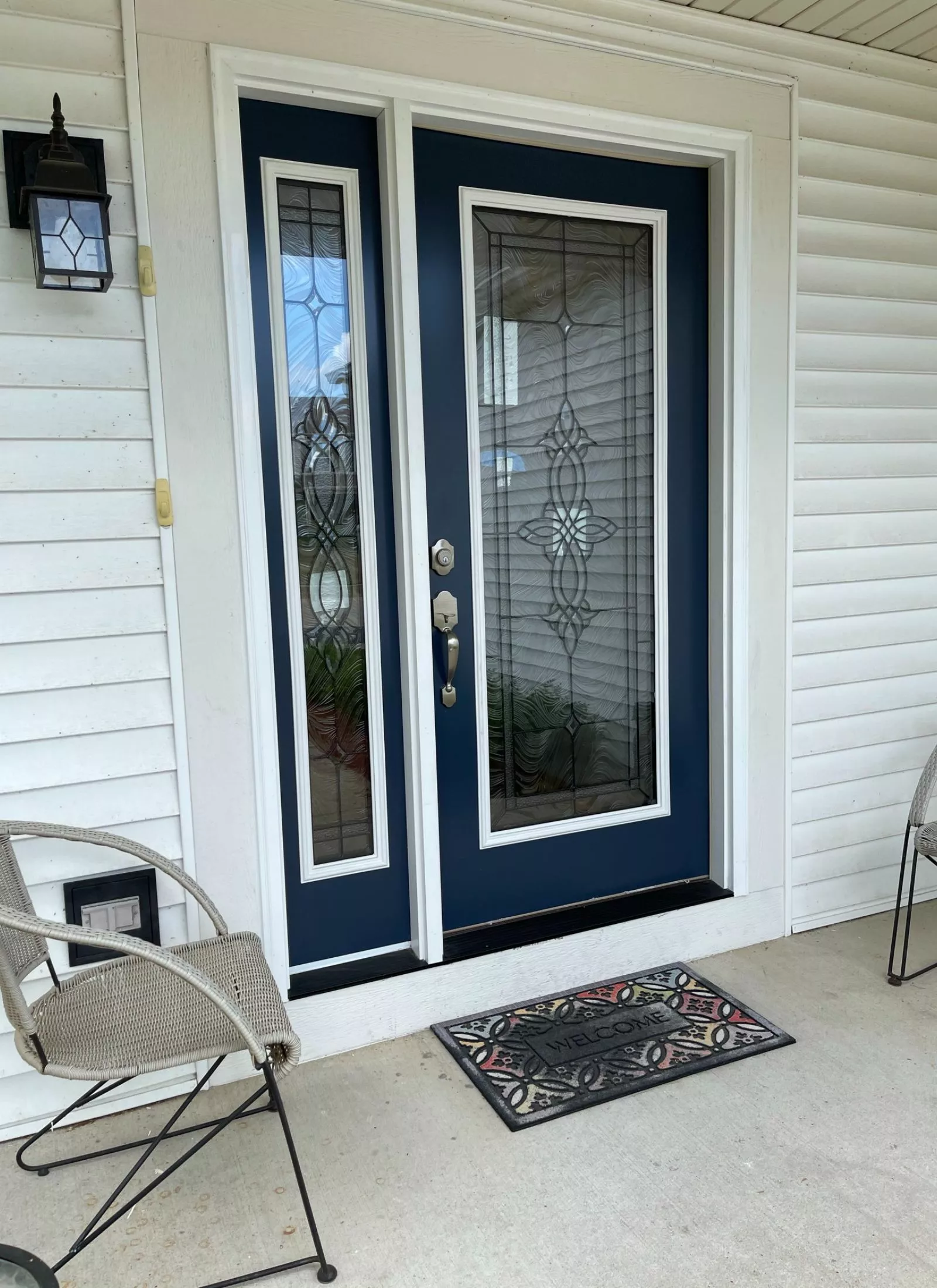 A home renovation with a blue front door and two chairs on it.