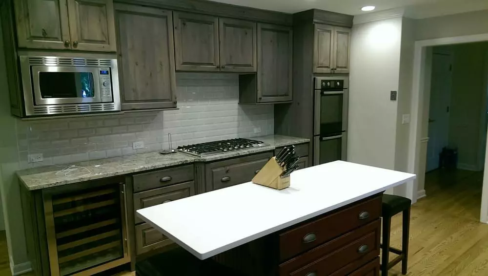 A kitchen with gray cabinets and a counter top undergoing a home renovation.