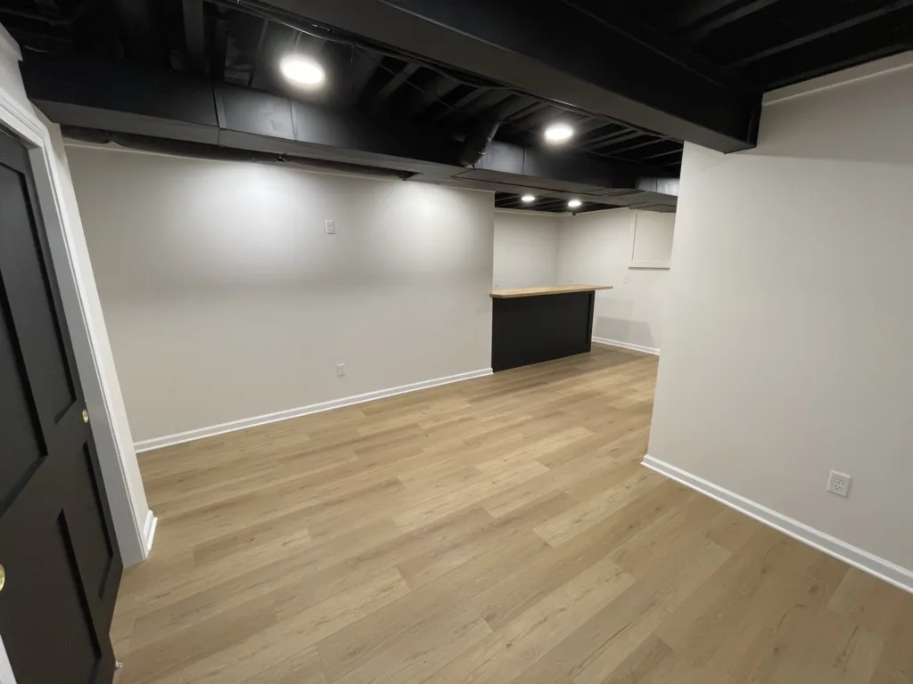 An empty basement with wood floors and black walls, perfect for a home renovation project involving carpentry.