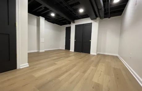 A gurnee finished basement - an empty room with wood floors and black walls.