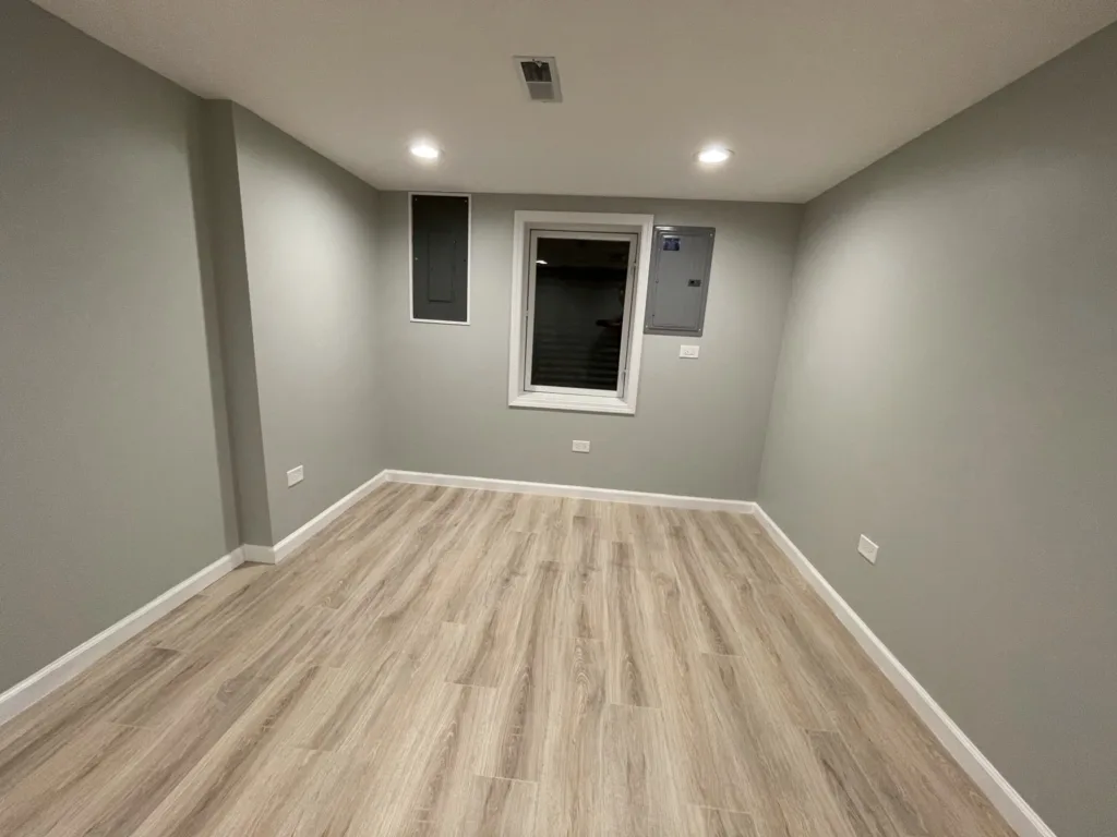 An empty room with gray walls and wood floors, undergoing a home renovation.