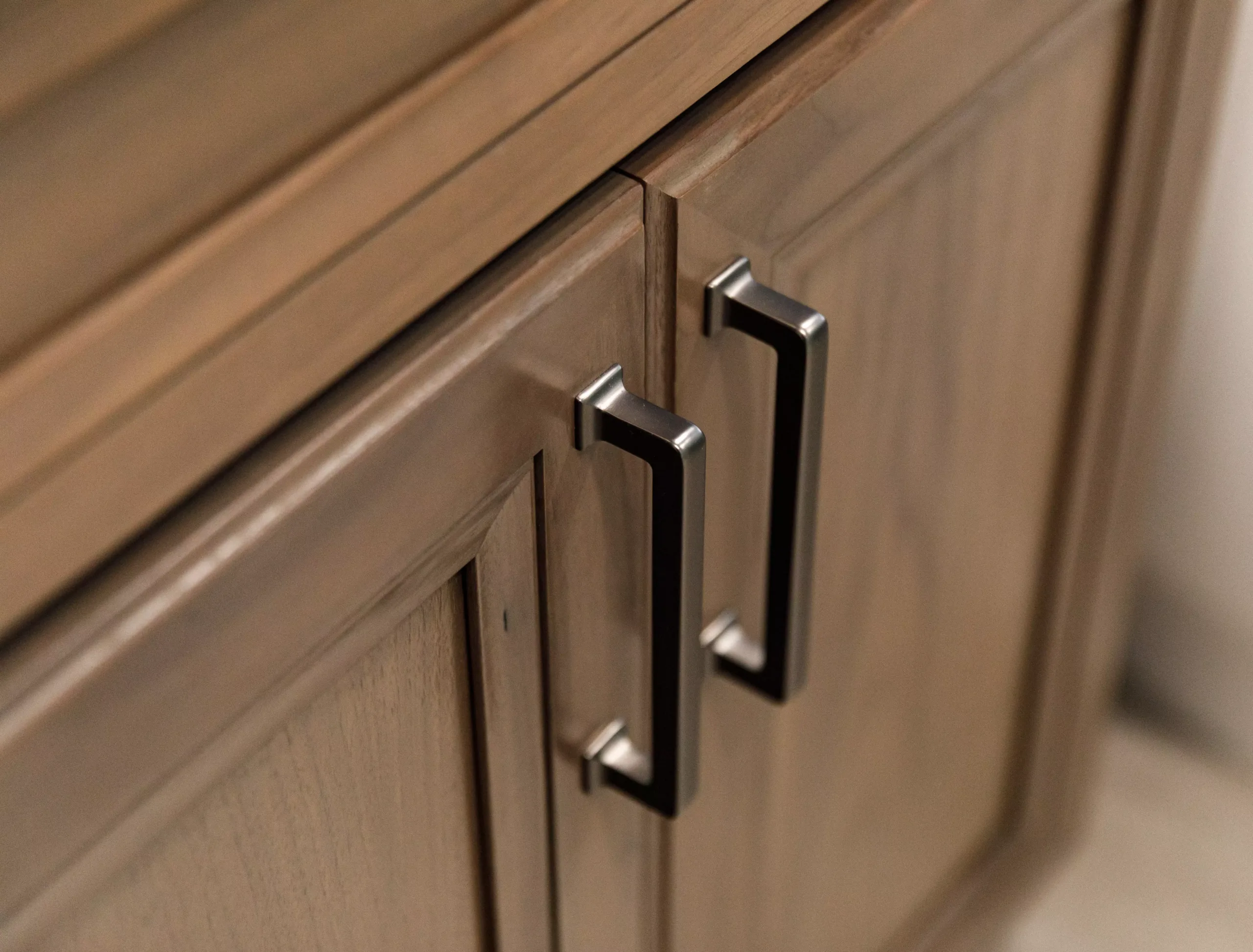 This close up showcases a beautifully crafted wooden cabinet, adorned with sleek metal handles.