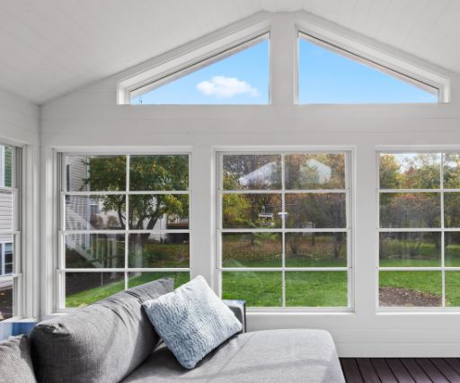 A sunroom with large windows and a couch, perfect for carpentry and bathroom renovation projects.