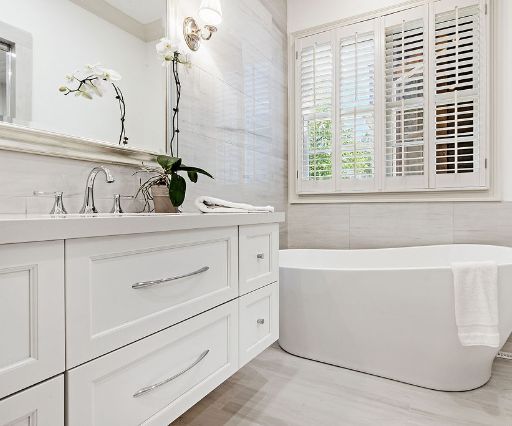 A white bathroom with a tub and sink undergoing a bathroom remodel.