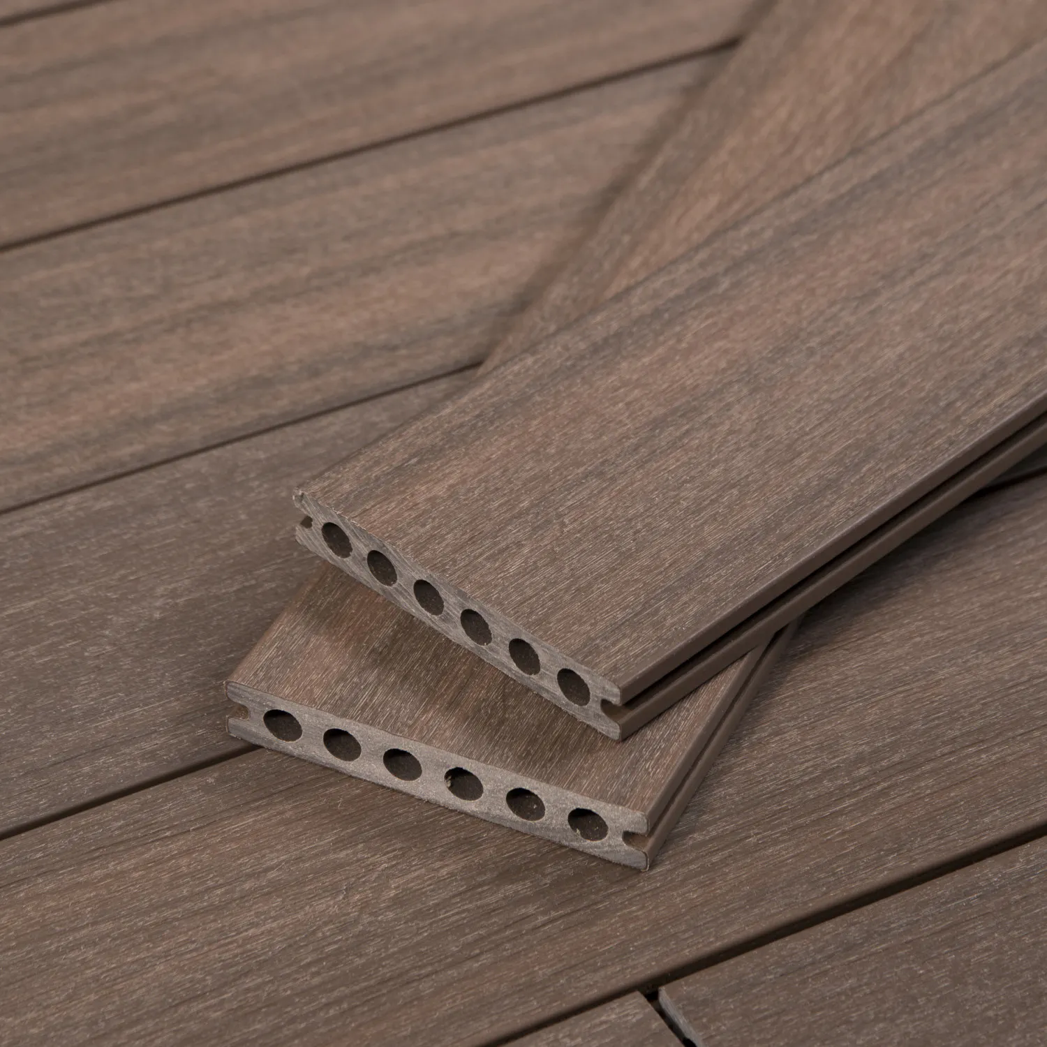 Wood-textured laminate flooring planks with interlocking edges designed for next deck types of decking, sitting on a wooden surface.